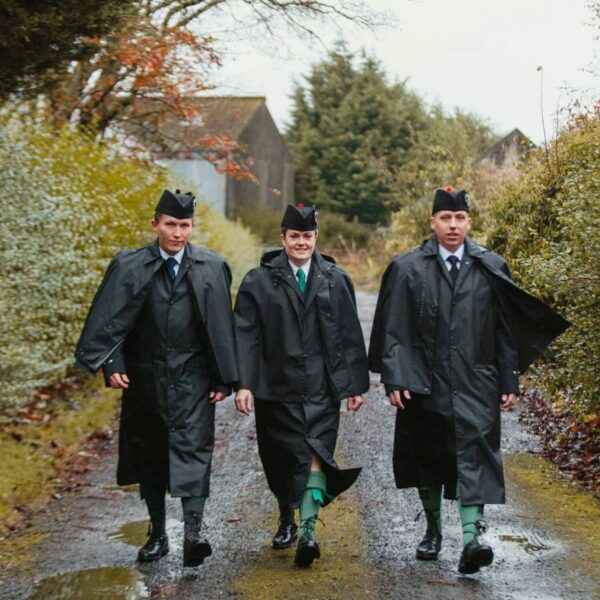 Three men wearing Bandspec Inverness Rain Capes walking down a path.