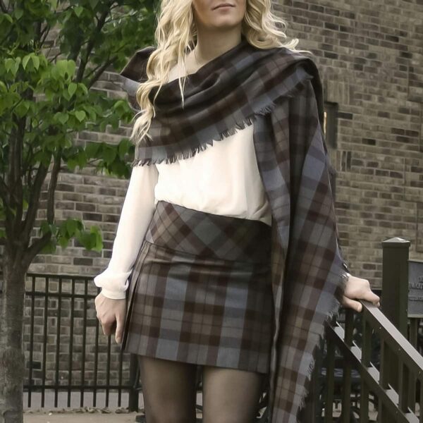 A woman in a plaid skirt strikes a pose while donning a Light Weight 11oz Wool Tartan Stole for a picture.