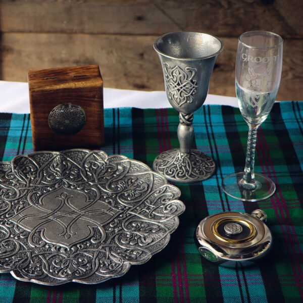 A silver plate sits on a table next to a glass of wine.