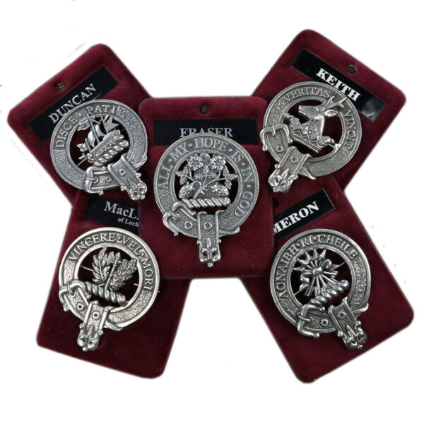 Image of five Pewter Clan Crest Cap Badges/Brooches from Scotland, each displaying a different clan name: Duncan, Fraser, Keith, Cameron, and one partially obscured. The badges are elegantly presented on dark red velvet backing.