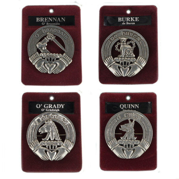 Displayed are four Irish Family Crest Cap Badge/Brooches on maroon velvet backings, labeled Brennan, Burke, O'Grady, and Quinn. Each badge features a unique emblem and decorative Irish Gaelic names.