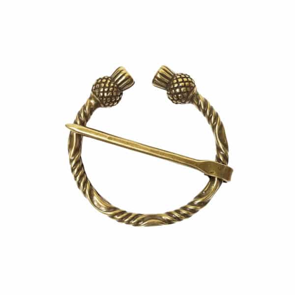 The Thistle Penannular Brooch crafted from brass showcases a twisted design, adorned with two thistle-shaped ends and an attached pin.