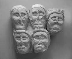 Four Celtic stone faces on a wall.