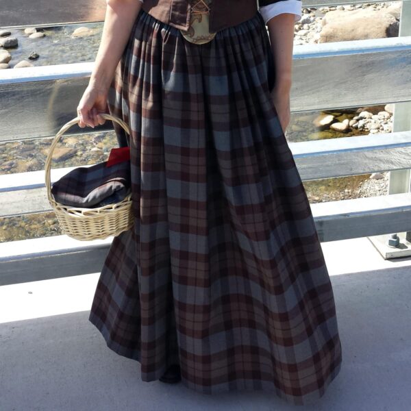 A woman in an OUTLANDER Gathered Skirt Authentic Premium Wool holding a basket on a bridge.