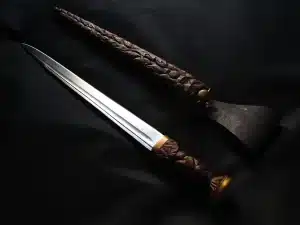 Scottish dirks, a wooden sword, and a wooden axe on a black surface.