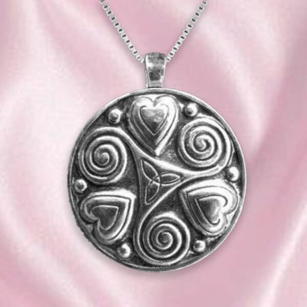 The Lovers Spiral Hearts Sterling Silver Pendant, featuring intricate heart and spiral designs set against a pink fabric background, exudes romance with its elegant attachment to a silver chain.