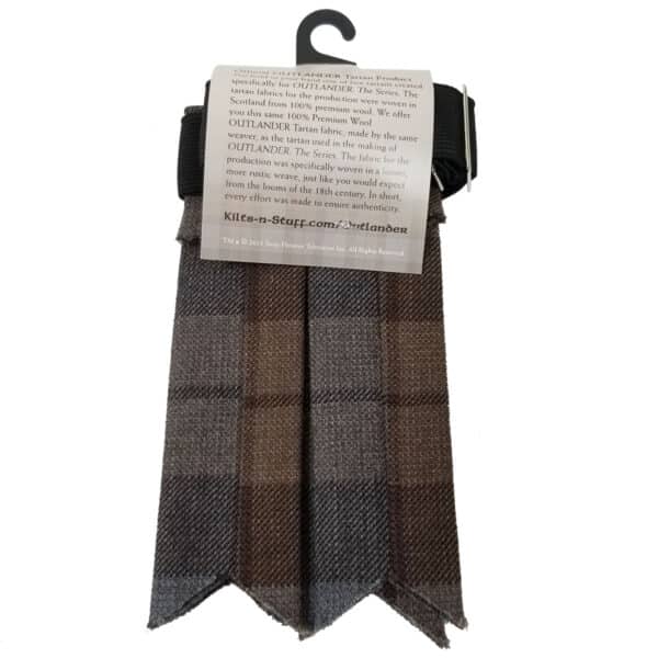 Image of a brown and grey plaid wool scarf on a white background, with a product tag detailing its traditional Scottish design and connection to the "Outlander" series. This Outlander Premium Wool Tartan Flashes accessory showcases the timeless charm of tartan flashes.