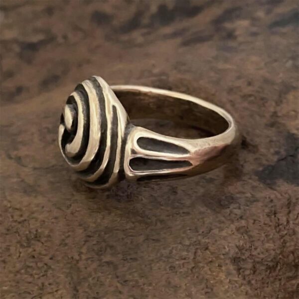 A Triskele Ring with a spiral design on it.