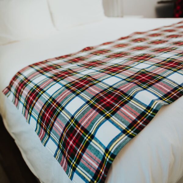 A Stewart Dress Tartan bed runner on a bed in a hotel room.
