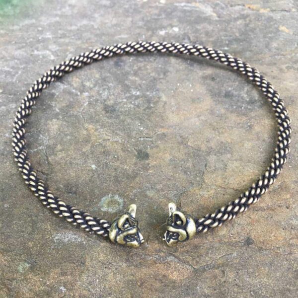 Two Cat Bronze Torc - 16inch Light Braid 6mm bracelets featuring a captivating cat and torc design beautifully displayed on a smooth stone surface.
