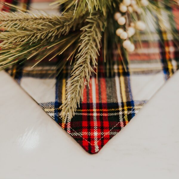 A plaid placemat with pine branches on it, perfect for adding a touch of Stewart Dress/MacKenzie Tartan Mantel Runner - Homespun Wool Blend to your table setting.