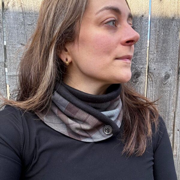 A woman wearing a black shirt and an Outlander Neck Warmer Cowl Scarf - Premium Wool in plaid.