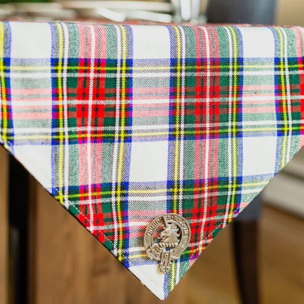 A plaid tablecloth with a scottish kilt on it surrounded by the Black Watch Ancient/Solid Green Reversible Tartan Table Runner - Homespun Wool Blend.