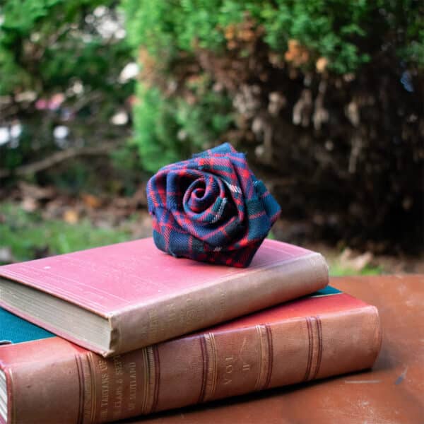 A Light Weight 11oz Premium Wool Tartan Rose sits on top of a stack of books.