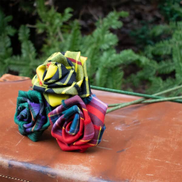 Three Light Weight 11oz Premium Wool Tartan Roses sitting on top of a wooden table.