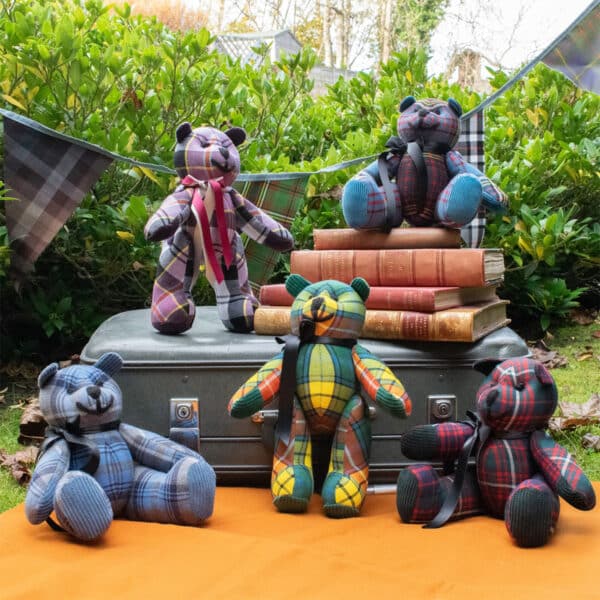 A group of teddy bears sitting on a suitcase covered in Light Weight 11oz Premium Wool Tartan Bear.