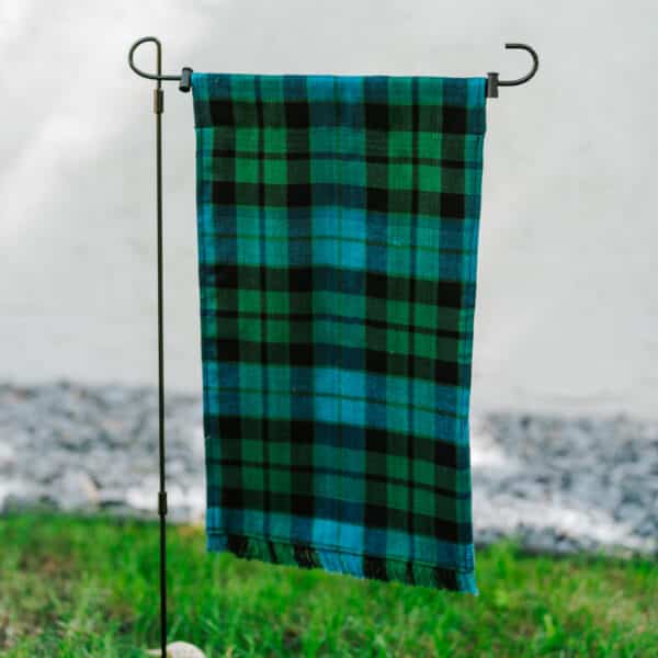 A MacKay Ancient Tartan Garden Flag - Homespun Wool Blend, black and green plaid, hanging on a pole.