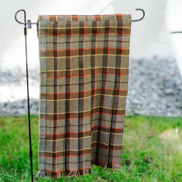 An Outlander Tartan Garden Flag - Homespun Wool Blend hanging on a pole in the grass.