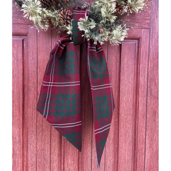 A Tartan Wreath Sash - Homespun Wool Blend hangs on a red door.