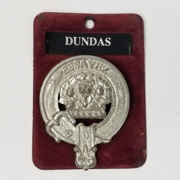 A silver Dundas Pewter Clan Crest Cap Badge with the name dundas on it.