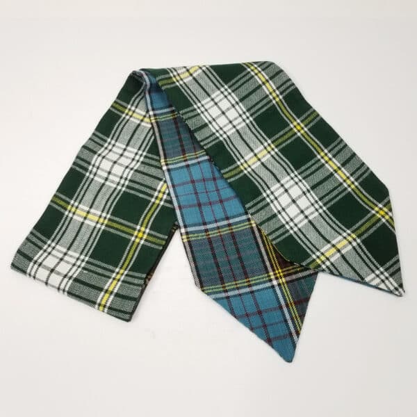 A reversible tartan mantel runner in green, blue, and yellow on a white surface.