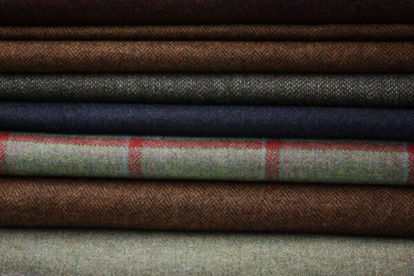 A collection of Herringbone Tweeds featuring a variety of colors and patterns, including plaids and solid weaves.