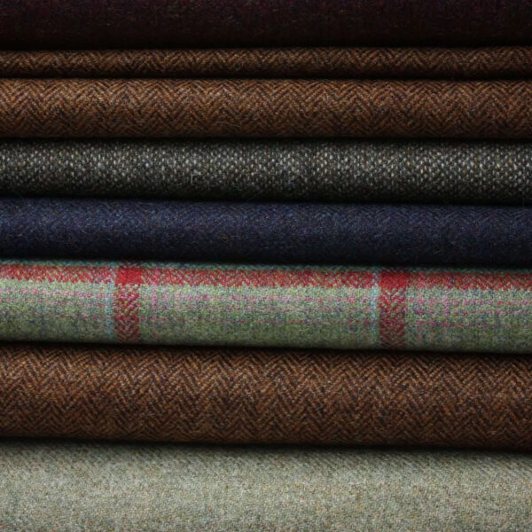 A collection of Herringbone Tweeds featuring a variety of colors and patterns, including plaids and solid weaves.