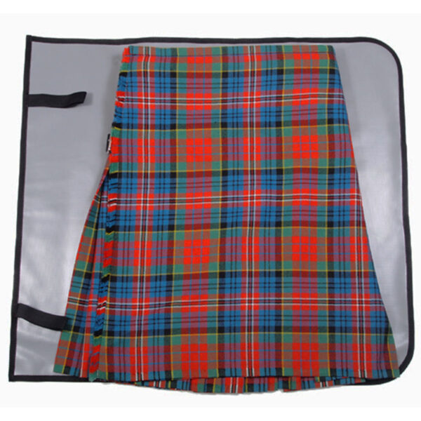 A Deluxe Kilt Carry Roll, showcasing a vibrant red, green, and blue plaid pattern with pleats, is displayed on a flat grey surface. The roll includes black straps on the left side for secure fastening.