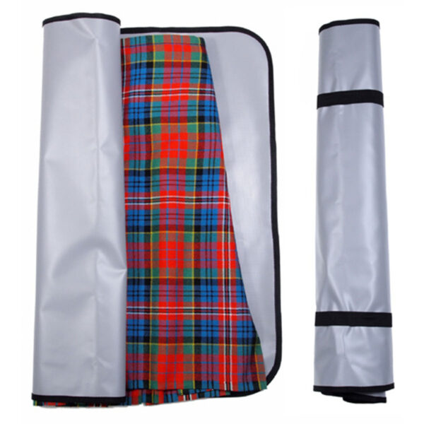 Presenting the Deluxe Kilt Carry Roll, a picnic blanket with a vibrant plaid pattern in red, green, blue, and yellow akin to a traditional kilt on one side and a simple gray surface on the other. It is displayed both partially unrolled and fully rolled for convenient carrying.