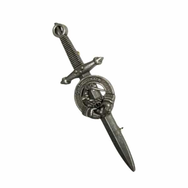 The Brennan Irish Crest Kilt Pin is a silver-toned metal brooch, reminiscent of an Irish Crest, featuring a sword design with a circular emblem at its hilt, depicting a helmet and a hand grasping the sword.