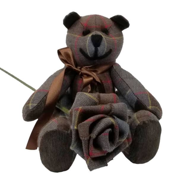 An Outlander Tartan Heritage Bear, adorned with a brown bow, sits holding a fabric rose. Both the bear and the rose are expertly crafted from matching lightweight 11oz premium wool tartan fabric.