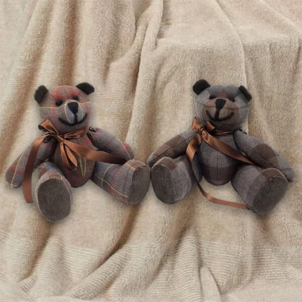 Two Outlander Tartan Heritage Bears & Roses, featuring brown ribbons and crafted from lightweight 11oz premium wool tartan, are seated on a beige blanket.