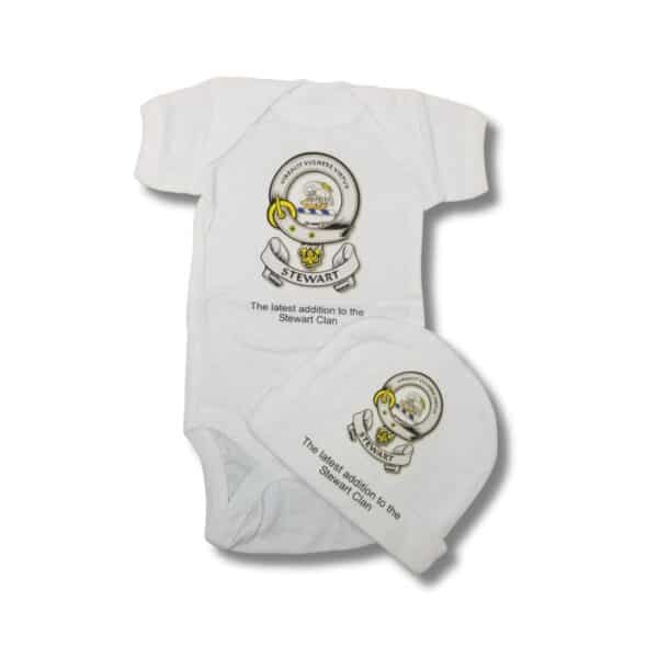 This Gordon Clan Onesie & Hat Set features a white baby clothing ensemble, including a onesie and hat, adorned with the family crest and the phrase "The latest addition to the Gordon Clan.