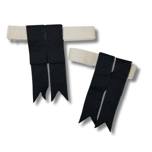 Product Description: A pair of white elastic bands with small black ribbon tails attached, ideal for children. The ribbons feature V-shaped ends, adding a subtle flair that catches the eye with a hint of playful style.