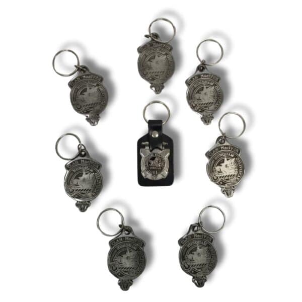 Eight metal keychains featuring similar ornate designs are arranged in a circle around the Armstrong Clan black leather keychain, which honors Scottish heritage with its central badge.