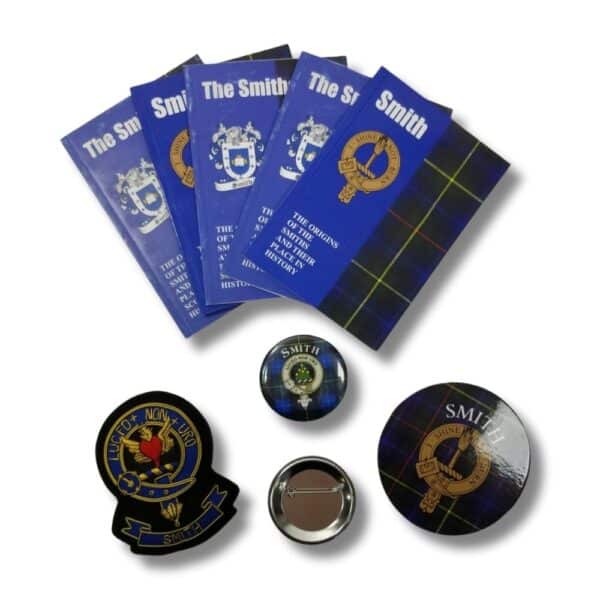 Set of four blue booklets titled "Armstrong Clan" featuring crest designs, accompanied by various Armstrong-themed badges and a magnet, celebrating Scottish heritage and paying tribute to the Armstrong Clan.