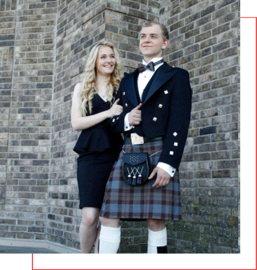 A couple in a kilt standing next to a brick wall, showcasing the perfect attire for buyers seeking a kilt.