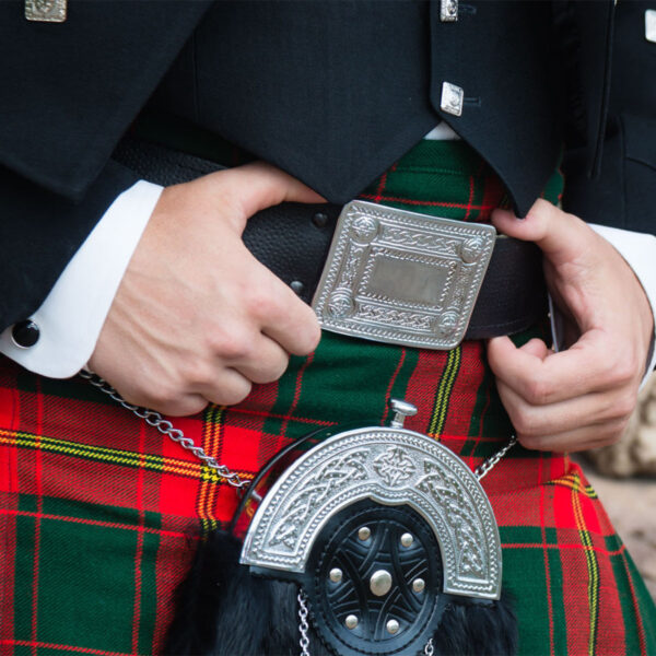 A man wearing a kilt accessorized with a Celtic Knot Kilt Belt Buckles.