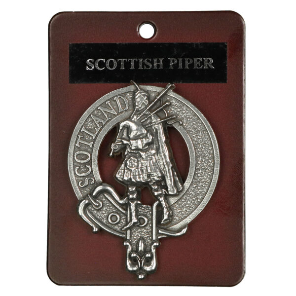 A Scottish Piper Cap Badge/Brooch on a red tag.
