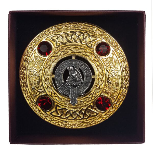 A Clan Crest Plaid Brooch with red stones in a box.