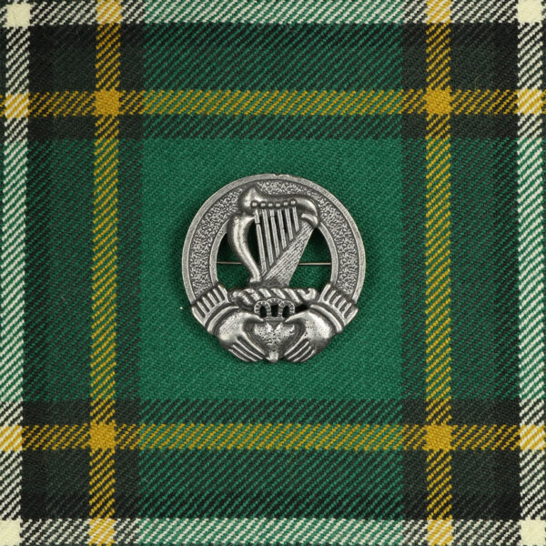 An Irish Harp Cap Badge/Brooch on a green tartan.