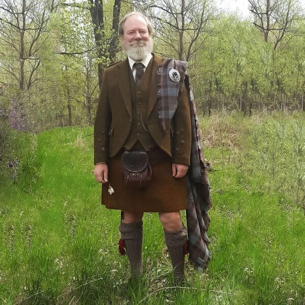 A man in a Braemar Tweed Jacket and Vest Set standing in a field.