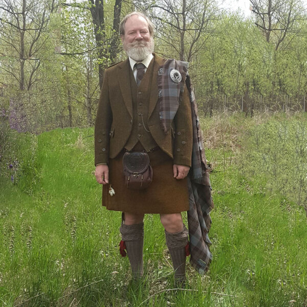 A man in a Braemar Tweed Jacket and Vest Set standing in a field.
