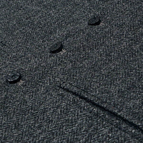 A close up image of a grey wool coat with buttons and a Tweed 5 Button Vest.