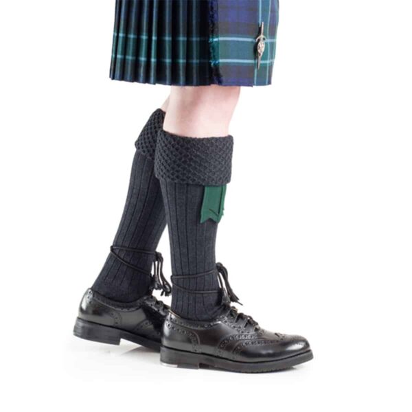 A Piper Kilt Hose wearing a kilt and black shoes.