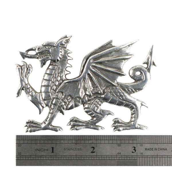 An image of a Welsh Dragon Pewter Plaid Brooch on a ruler, adorned with a silver plaid brooch.