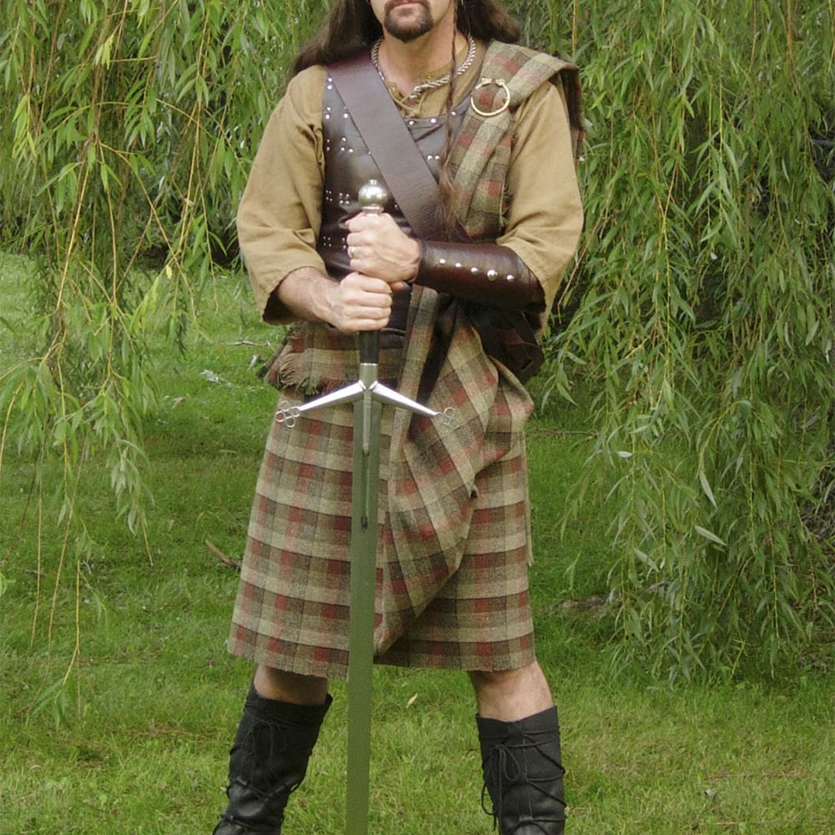 A man in a Welsh Tartan Medium Weight Premium Wool Ancient Kilt holding a sword.
