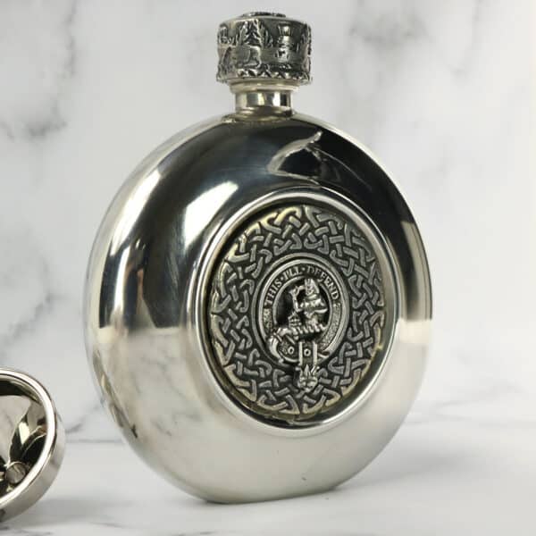 A silver flask with a scottish clan emblem on it.