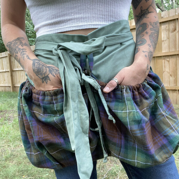 A woman with tattoos wearing a plaid apron.