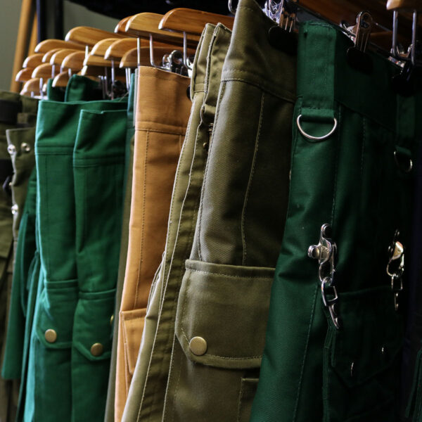 A row of green and brown pants hanging on a rack.